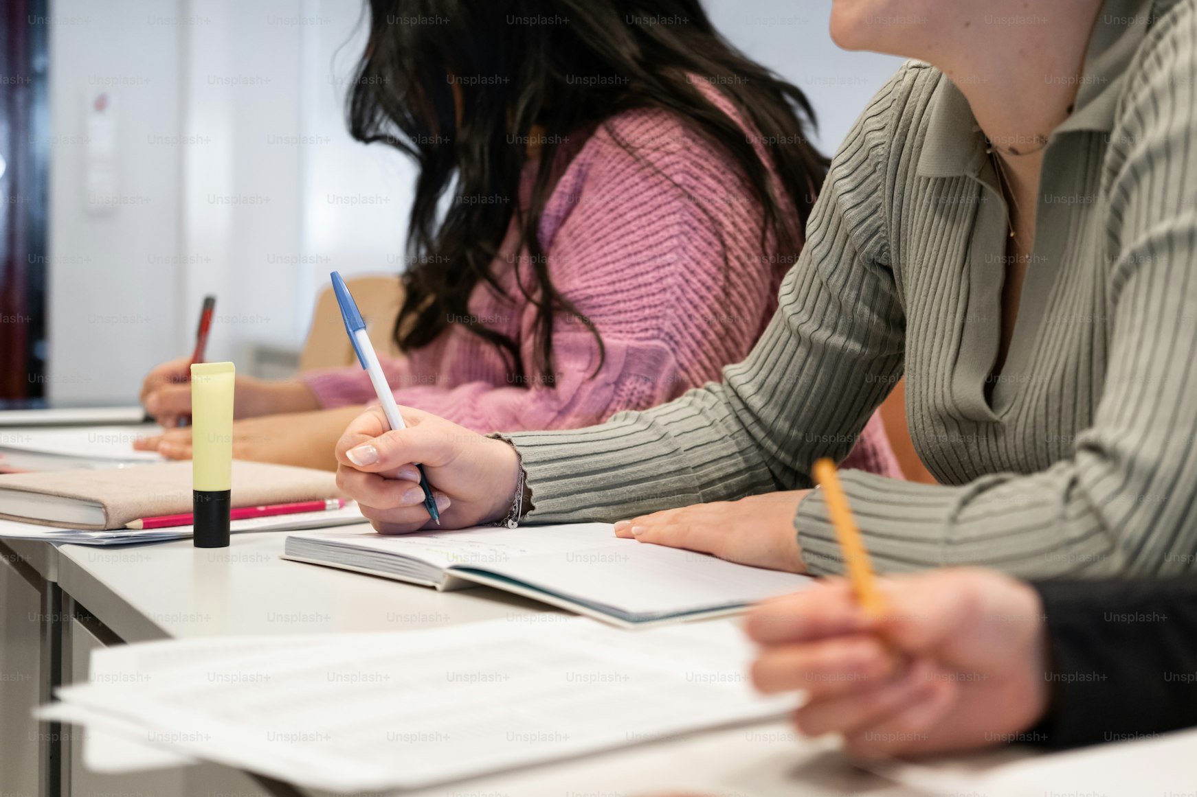 Alunos a escrever num teste, com cadernos e canetas sobre a mesa