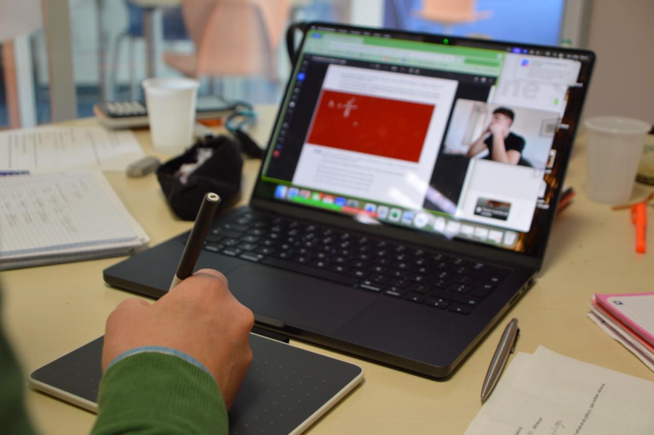 Aluno numa aula online do TIN, com mesa digitalizadora e o professor em videochamada